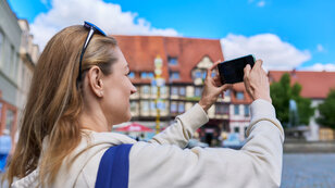 Touristin fotografiert Altstadt mit dem Smartphone