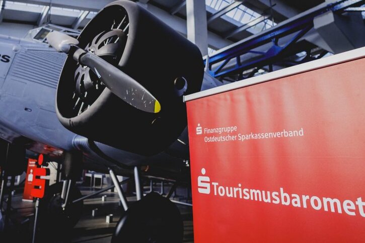 Flugzeug in Technikmuseum und rechts Roll-up mit Aufschrift Tourismusbarometer