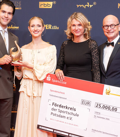 Nikita Volodin und Minerva Hase zeigen ihre Goldene Henne, rechts daneben zeigt DSGV-Präsident Dr. Ulrich Reuter den Scheck für die Eliteschule des Sports in Potsdam