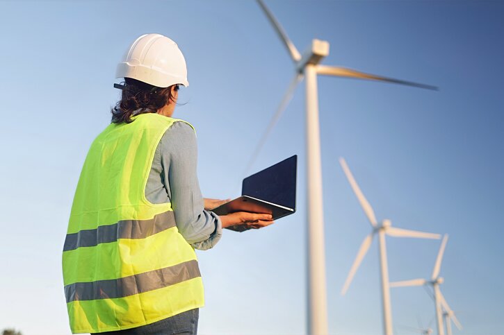 Foto: Adobe Stock/NJF Arbeiterin mit Computer vor Windkraftanlage